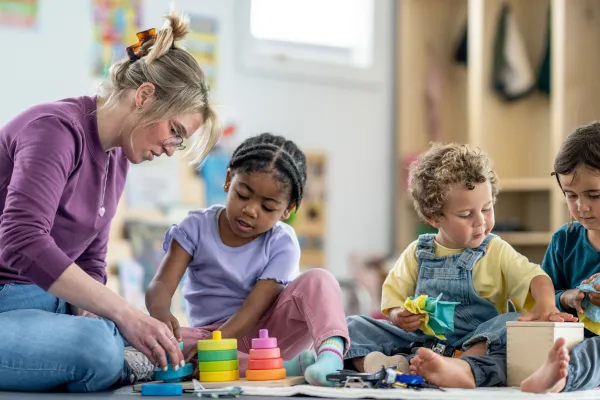 An image of a woman at a daycare center interacting with 3 toddlers