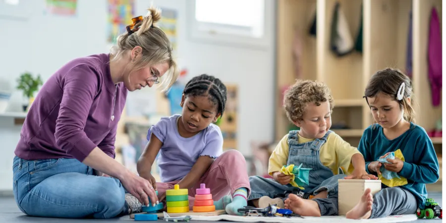An image of a woman at a daycare center interacting with 3 toddlers