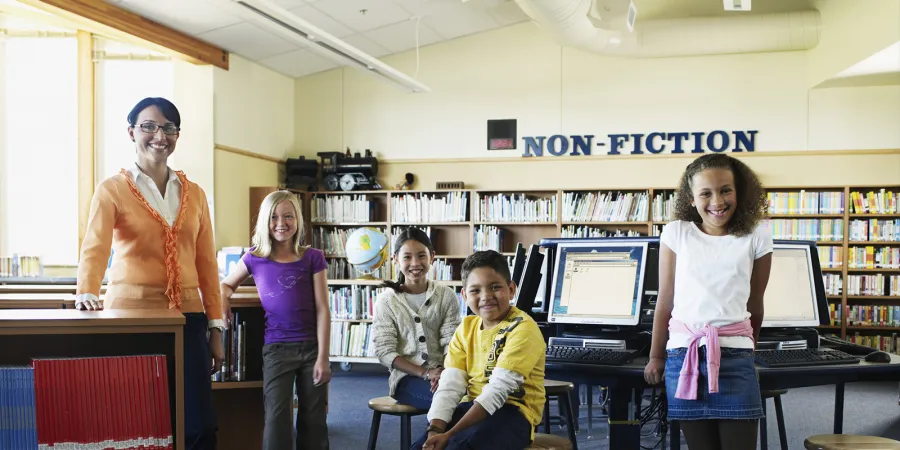 A librarian and 4 students are inside a library.